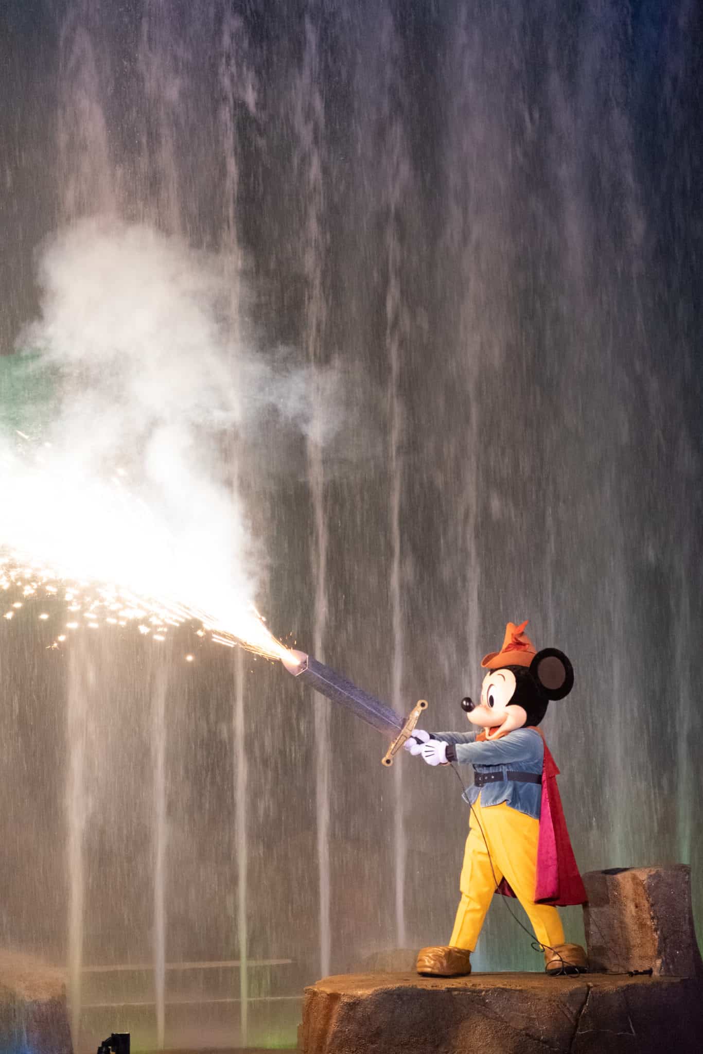 Sorcerer Mickey wielding a sword surrounded by fire and lights during the Fantasmic! show at Hollywood Studios