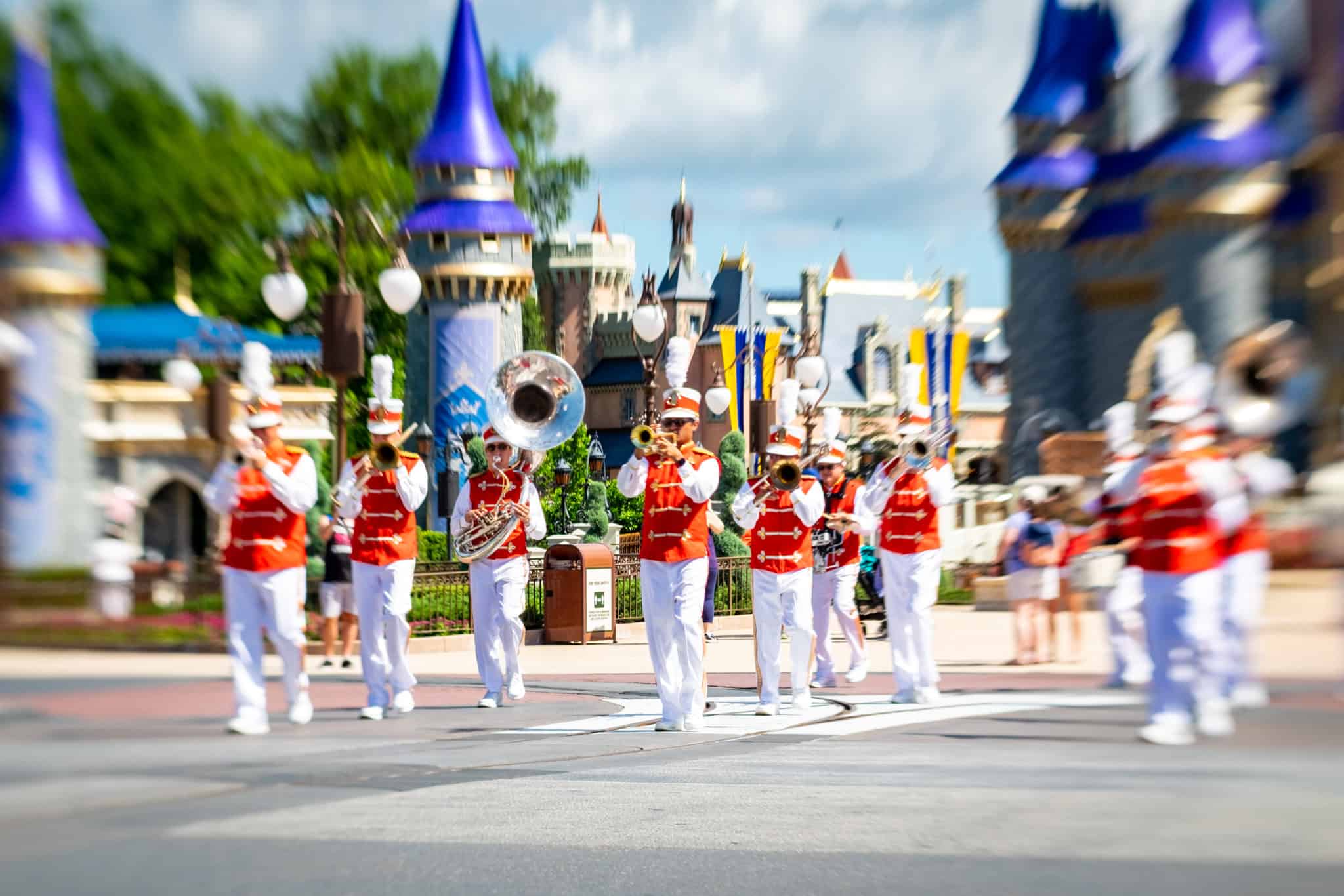 Characters and performers in a cavalcade procession down Main Street at Magic Kingdom with castle in background
